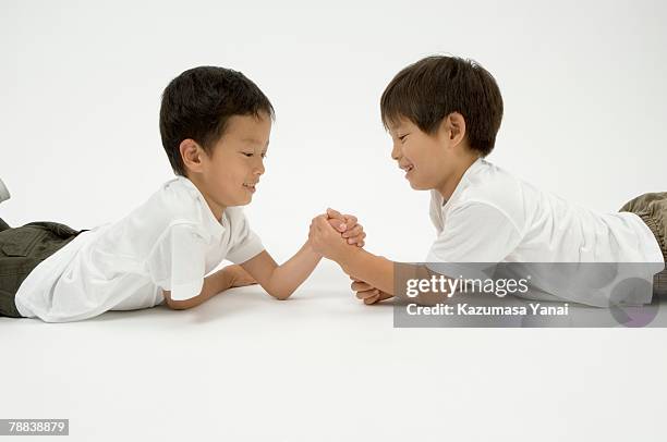 two elementary age boys arm wrestling - boys wrestling stock pictures, royalty-free photos & images