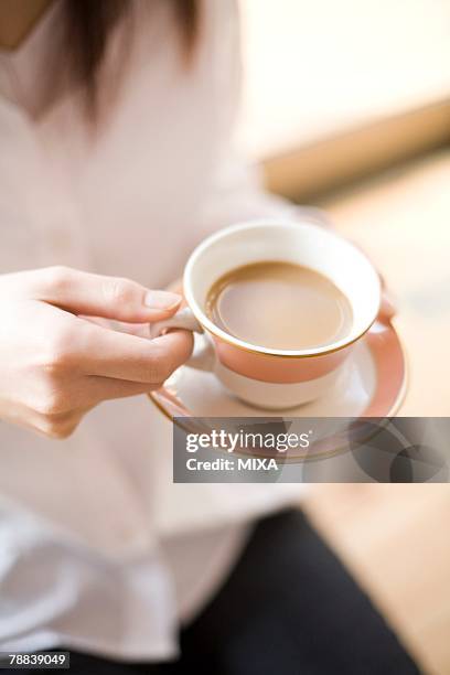 young woman having cup of coffee - untertasse stock-fotos und bilder