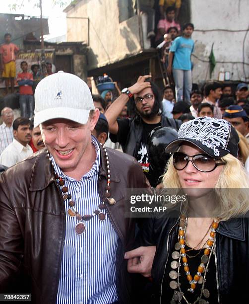 Multiple Grammy award winning pop star Madonna , along with her director husband Guy Ritchie, walks through a slum after arriving on a chartered...