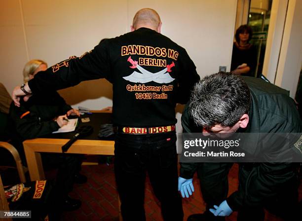 Policeman checks a member of the biker group 'Bandidos' outside the district court on January 9,2008 in Muenster, Germany. The two biker groups at...