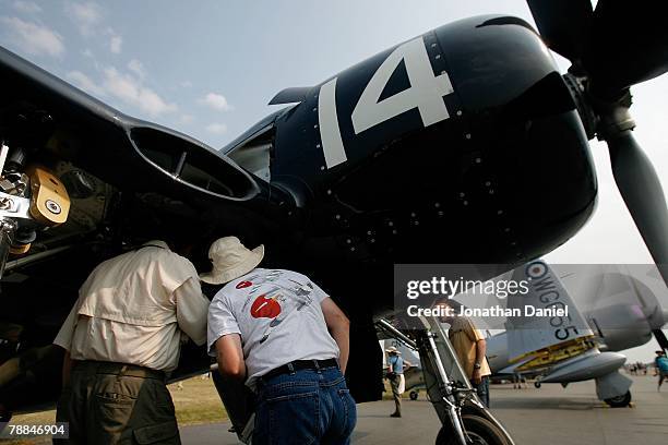 Airplane enthusiasts look into the wheel well of a post World War II-era F6F Bearcat fighter during the Experimental Aircraft Association's 2007...