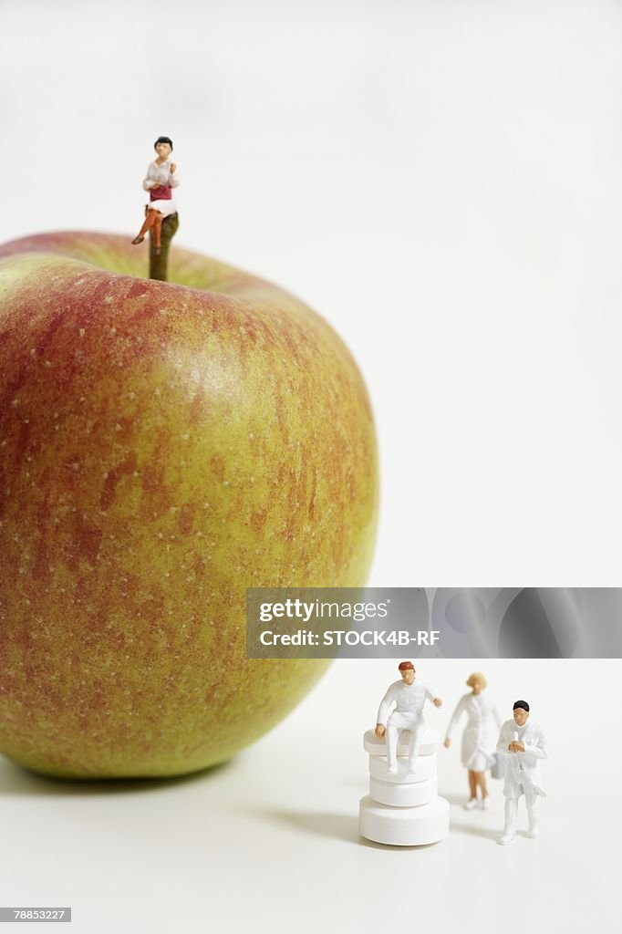 Female figurine on an apple, figurines of doctors beside