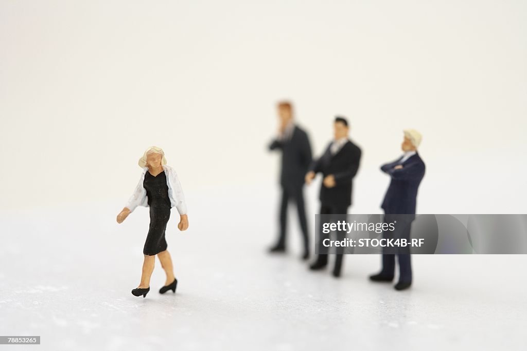 Businesswoman figurine, three businessmen figurines in background