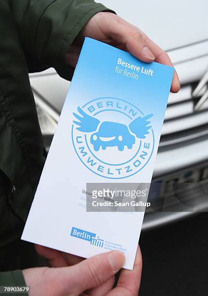 German policeman holds a flyer with information about Berlin's environment zone that he will hand out to drivers whose cars do not yet have an...