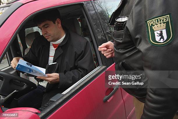 Driver, whose car does not yet have an environment zone sticker, reads a flyer with information about Berlin's environment zone that he received from...