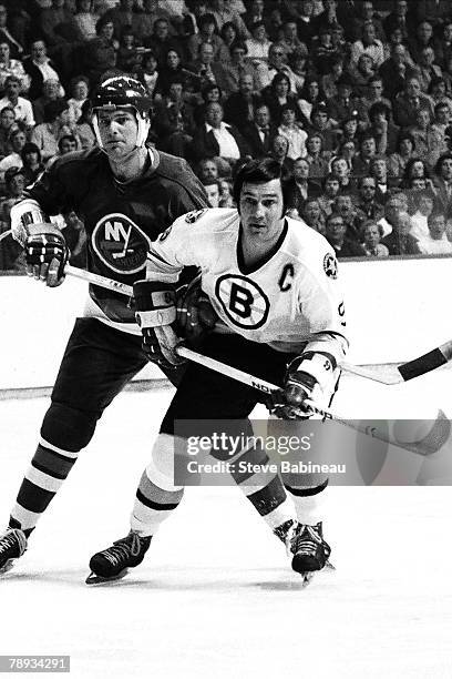 Johnny Bucyk of the Boston Bruins gets hooked by Bert Marshall of the New York Islanders.