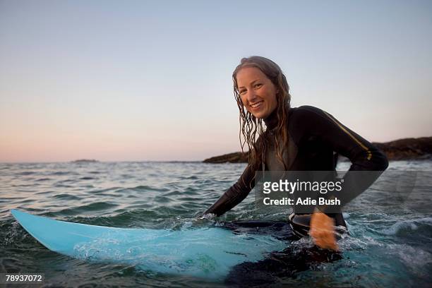 woman sitting on surfboard in the water smiling. - surfer portrait fotografías e imágenes de stock