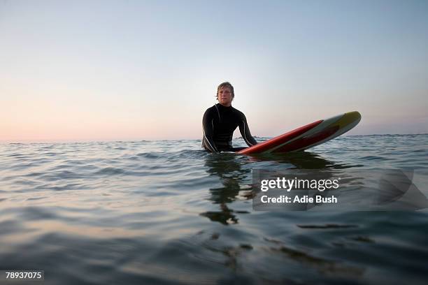 man sitting on surfboard in the water. - sitting on surfboard ストックフォトと画像