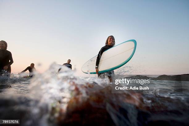 four people with surfboards in the water. - surfer portrait fotografías e imágenes de stock