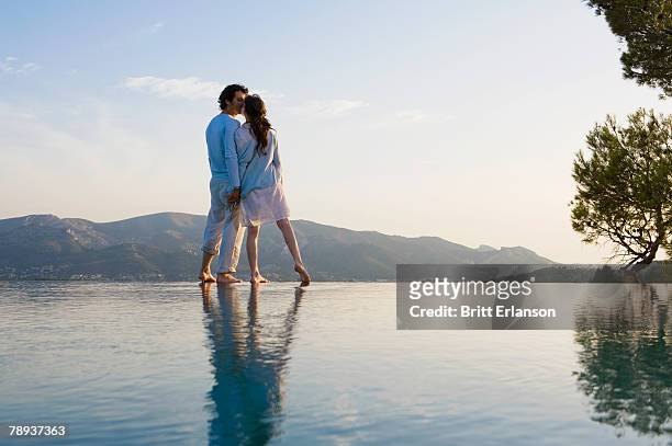 couple kissing and holding hands by infinity pool. - 馬賽族 個照片及圖片檔