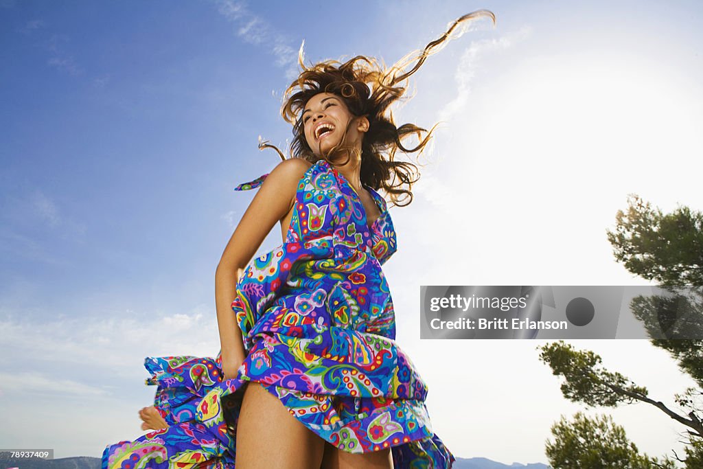 Woman laughing outdoors in a colorful dress.