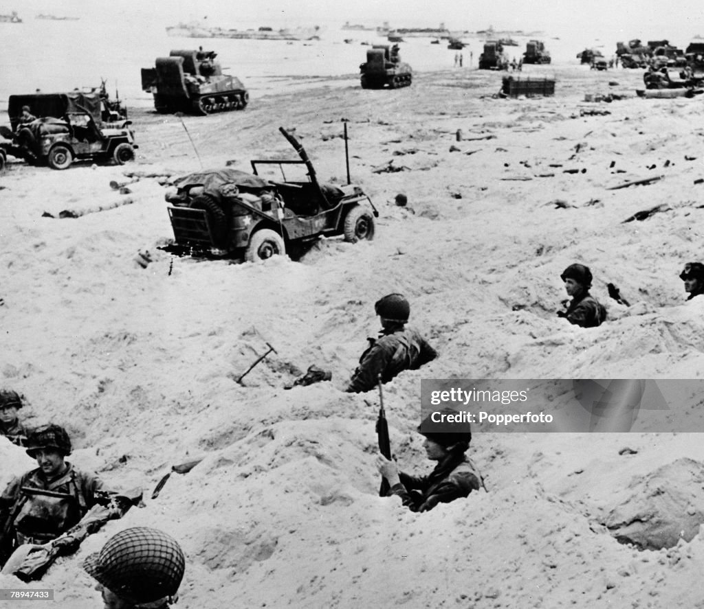 War & Conflict. World War Two. France 6th June 1944. American troops dig in on the Normandy beach head after the D Day Invasion. jeeps and tank units move off the beach.