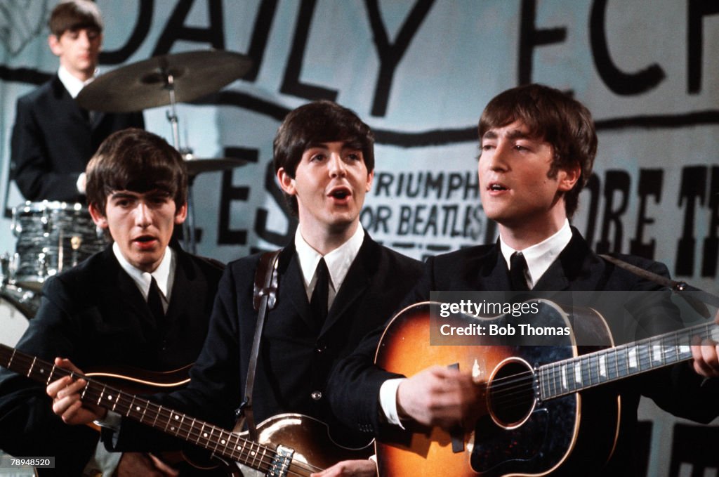 Volume 2. Page 85, Picture 1. 1963. The phenomenon that was the Beatles. Left to Right: Ringo Starr on drums, George Harrison on guitar, Paul McCartney on bass and vocals, and John Lennon on acoustic guitars and vocals.