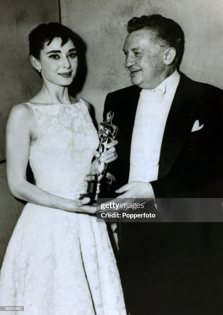 Stage and Screen. Personalities. pic: March 1954. Actress Audrey Hepburn receives her Oscar as Best Actress for her part in the film "Roman Holiday" from actor Jean Hersholt. Audrey Hepburn, (1929-1993) born in Brussels, a truly international star from a 