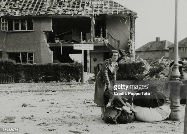 Scene in Croydon, south London, as a mother and her daughter wait beside their rescued belongings after a German bomb had damaged all the houses in...