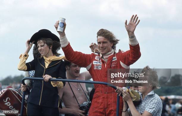 British racing driver James Hunt holds a can of Ind Coope Long Life beer as he waves to the crowd after driving the Marlboro Team McLaren McLaren M26...
