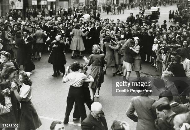 Crowd watches as young women and men dance together in Regent Street as the West End of London celebrates the end of conflict in World War II on...