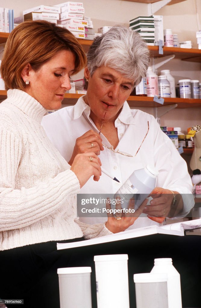 Stock Photography: Two pharmacists consulting over an item in the dispensary.