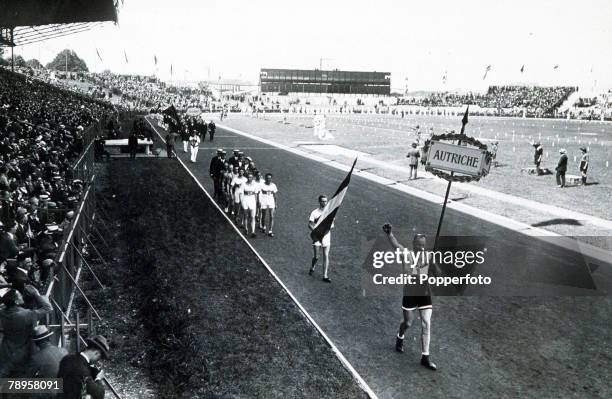 Spectators in the stands watch athletes from the Austria team take part in the Parade of Nations during the opening ceremony of the 1924 Summer...