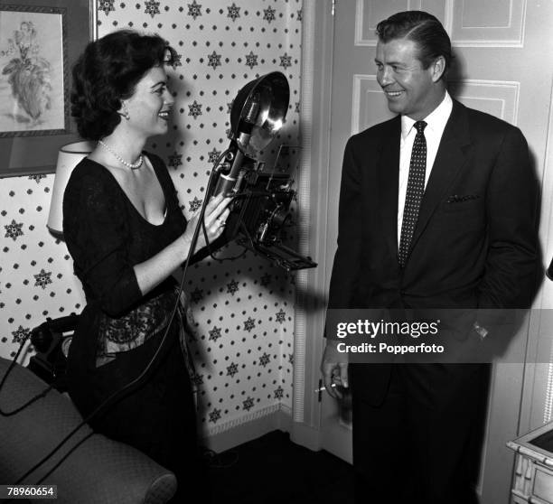 England American actress Faith Domergue is pictured taking a photograph of actor Gene Nelson at a press reception