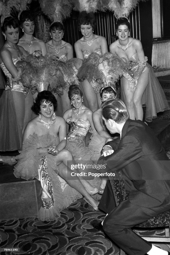 London, England. 1960. The Raymond Revuebar, Soho. Paul Raymond (back to camera), producer of nude shows at his club, is pictured talking with some of his dancers.