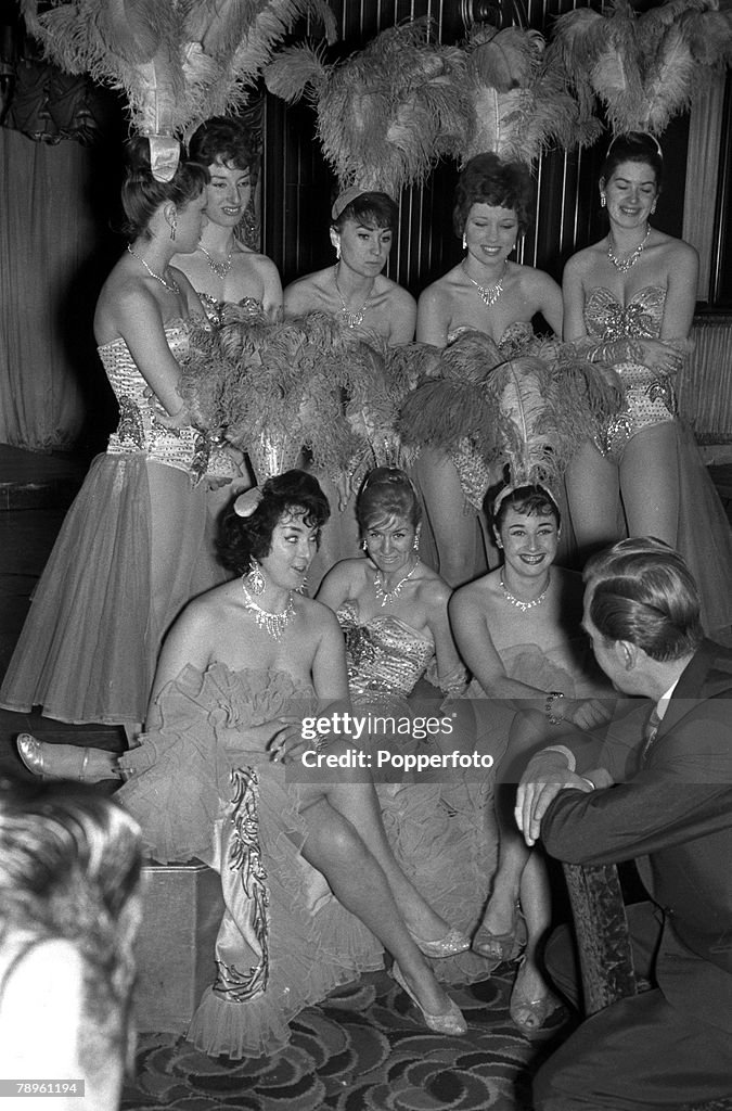 London, England. 1960. The Raymond Revuebar, Soho. Paul Raymond (back to camera), producer of nude shows at his club, is pictured talking with some of his dancers.