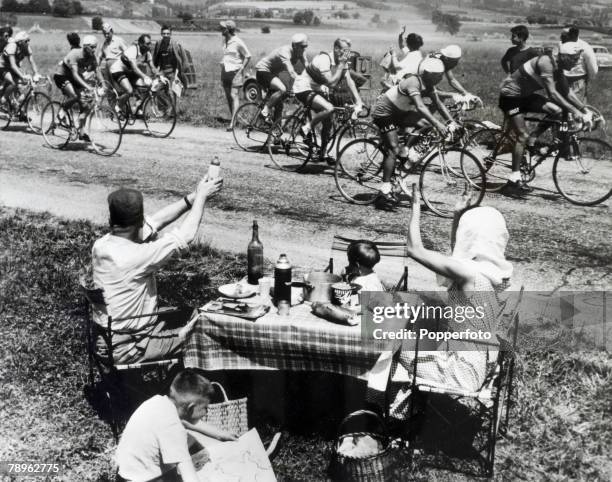 Sport, Cycling, France, Tour De France Bike Race A family eating at a table by the road wave to the riders and competitors as they pass during the...