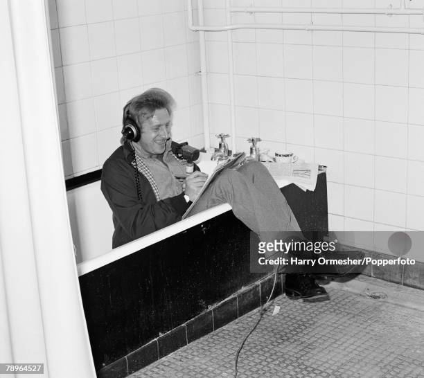Former international footballer Denis Law working for BBC Radio in the changing rooms at Anfield in Liverpool, England, circa 1980.