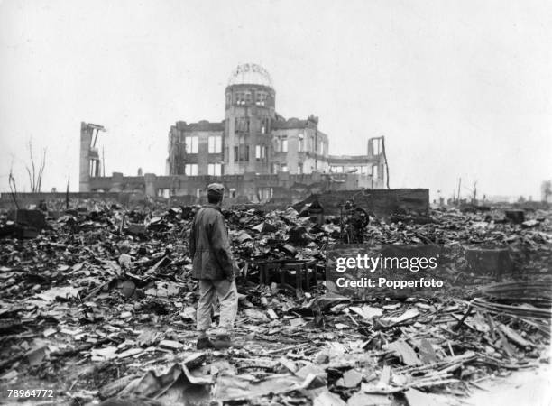 An Allied correspondent stands in the rubble, looking towards the ruins of the Hiroshima Prefectural Industrial Promotion Hall after the 6th August...