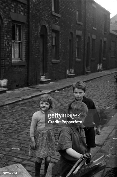 Manchester, England Three children are pictured playing in the streets of the Salford slums