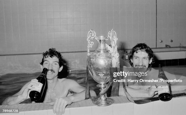 Graeme Souness and Terry McDermott of Liverpool pose with the League Championship trophy as they celebrate with champagne in the dressing room baths...
