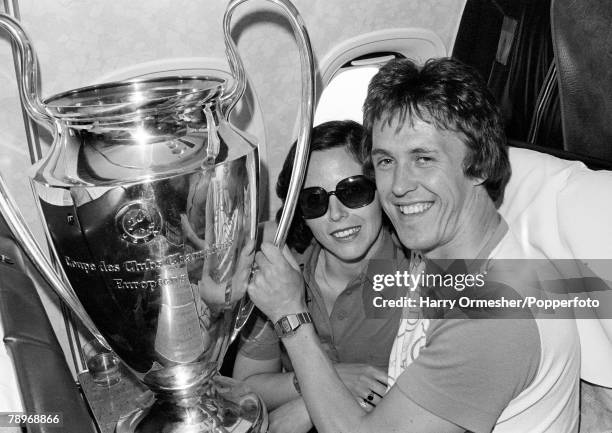 Liverpool footballer Phil Neal and his wife Sue, celebrate with the trophy during the flight home to Liverpool, the day after beating Borussia...