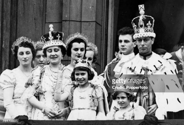 King George VI and Queen Elizabeth pictured wearing their crowns and coronation robes as they stand on the balcony of Buckingham Palace with Princess...