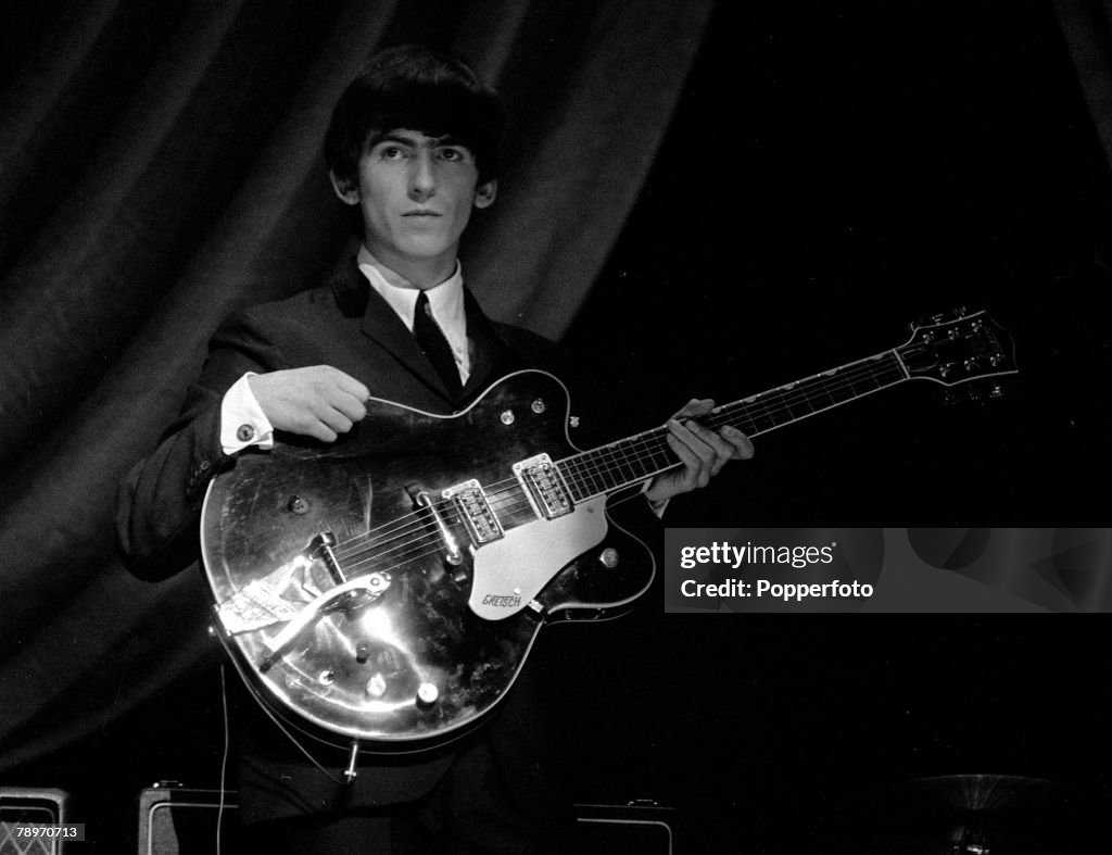 George Harrison of The Beatles pop group, holding his guitar during a rehearsal, 1963.