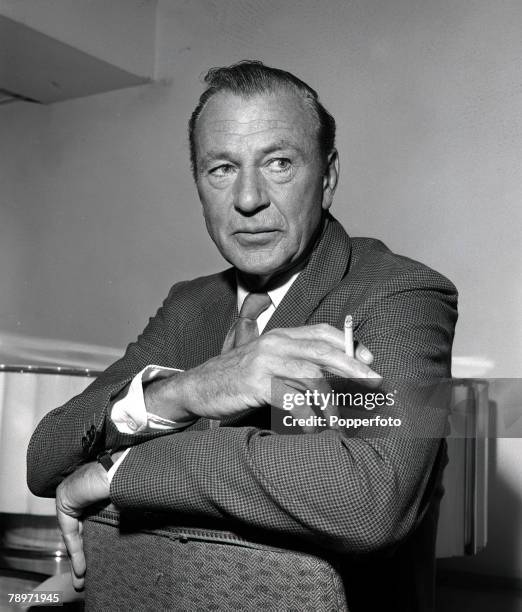 American actor Gary Cooper, arms folded and smoking a cigarette 1959