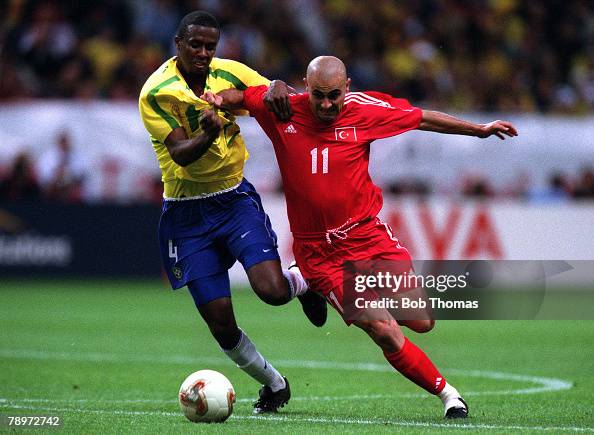 Football. 2002 FIFA World Cup Semi Final. Saitama, Japan. 26th June 2002. Brazil 1 v Turkey 0. Turkey's Hasan Sas is challenged by Brazil's Roque Junior.Credit: POPPERFOTO/JOHN McDERMOTT Football. 2002 FIFA World Cup Semi Final. Saitama, Japan. 26th June 2002. Brazil 1 v Turkey 0. Turkey's Hasan Sas is challenged by Brazil's Roque Junior.Credit: POPPERFOTO/JOHN McDERMOTT