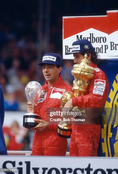 French racing driver Alain Prost pictured on right on the podium with the trophy after driving the Marlboro McLaren International McLaren MP4/2B...