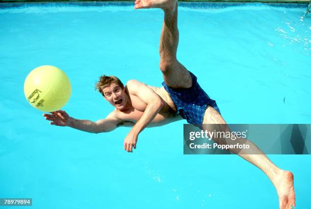 Stock Photography, A portrait of a young man leaping mid-air for a ball with legs stretched while he falls into a swimming pool