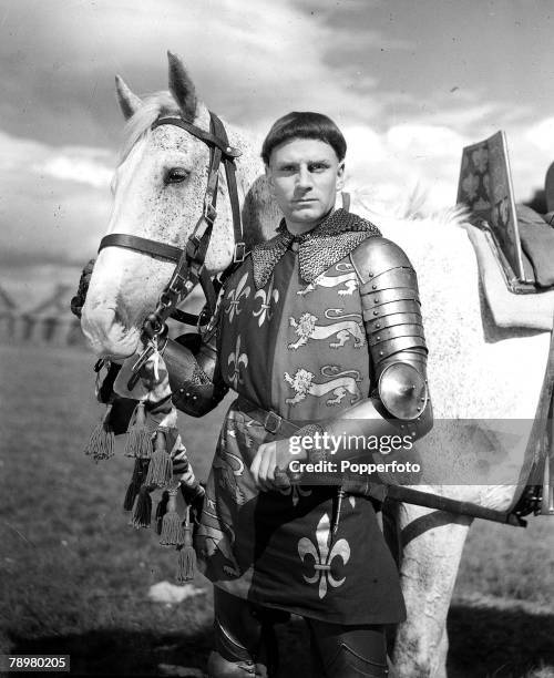 English actor and director Laurence Olivier with his grey gelding horse dressed in character as King Henry V of England prior to filming a scene...