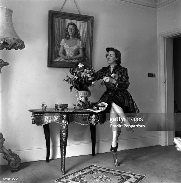 England, British singer Vera Lynn arranges flowers at a table in her home