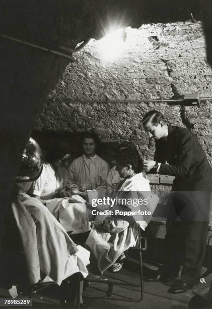 Life goes on as "normal" for a London hairdessers as a female client's hair is cut in the salon's underground shelter in the early days of The Blitz...
