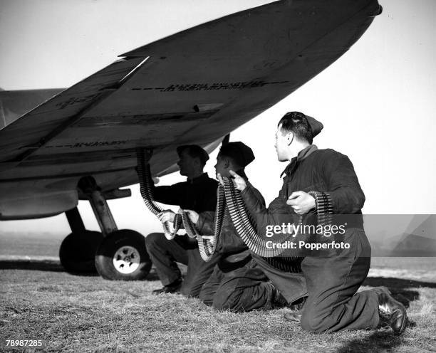 Royal Air Force mechanics load a long belt of .303 ammunition in to the wing of a Supermarine Spitfire to feed its Browning machine guns at a RAF...