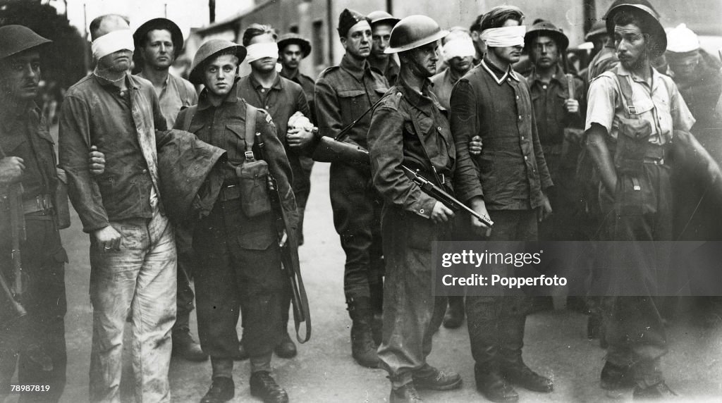 Krieg und Konflikt. Zweiter Weltkrieg. Der Dieppe-Angriff. Bild: August 1942. Kanadische Soldaten bewachen gefesselte deutsche Soldaten, die gefangen genommen und in einen britischen Hafen gebracht wurden. Der Angriff, bei dem sich die alliierten Streitkräfte zusammenschlossen, war ein kostspieliger Fehlschlag.