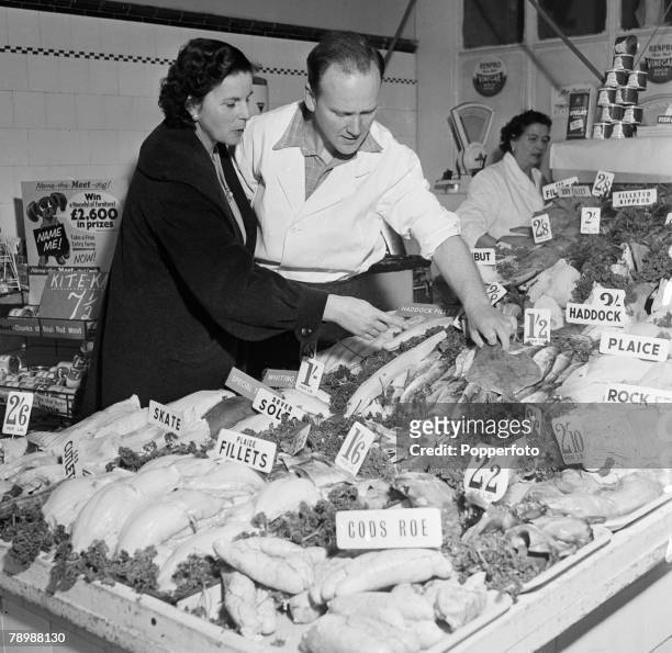 People, England, 1950's, A man serves a lady customer in a Fishmonger shop