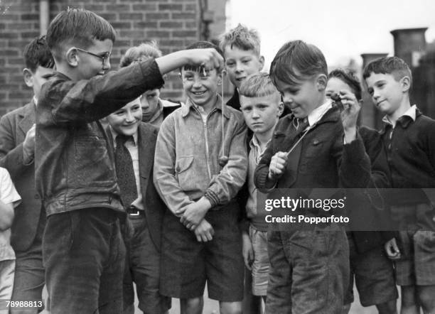 People, Children, pic: September 1952, Great Britain, Boys playing "conkers" in the street with other gathered around watching