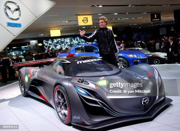 Mazda design director of Mazda North American operations Franz von Holzhausen motions to executives to join him as he poses with the Furai concept...