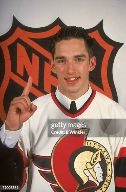 Canadian ice hockey player Alexandre Daigle signals 'number one' with his finger as he poses in an Ottowa Senators jersey at the NHL Entry Draft in...