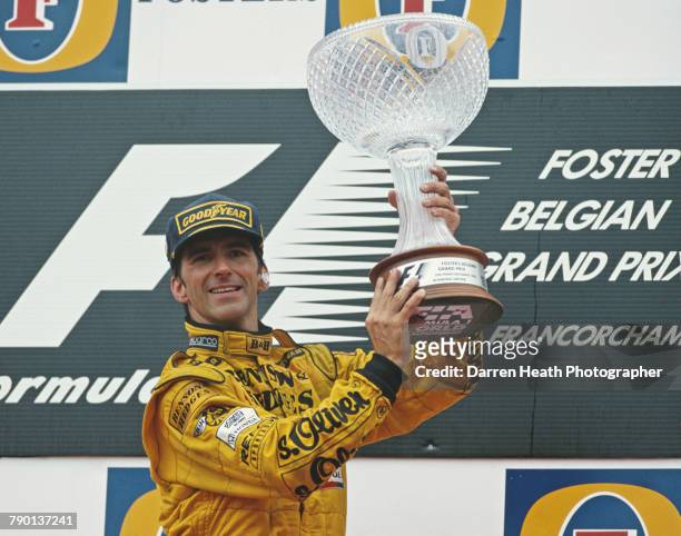 Damon Hill of Great Britain, driver of the B&H Jordan Jordan 198 Mugen Honda V10 holds the trophy aloft after winning the Formula One Belgian Grand...