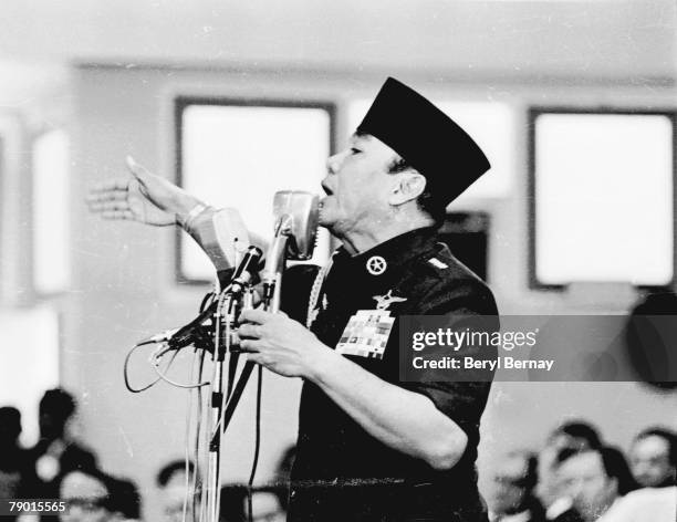 Indonesian President Sukarno , dressed in a military uniform, speaks from behind an array of microphones shortly after a series of attempted coups,...