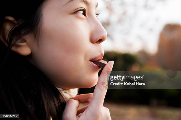 young woman eating piece of chocolate. - chocolate stock pictures, royalty-free photos & images